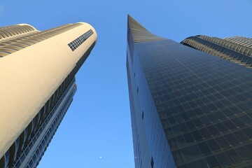 Two tall buildings of circular and triangular shape look up from below