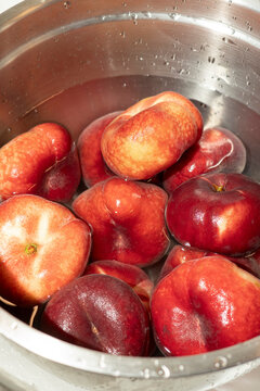 Flat Peaches Washed in Stainless Steel Bowl