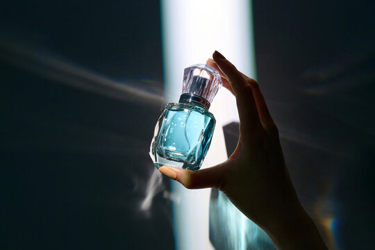 Hand Holding Elegant Perfume Bottle with Dramatic Lighting