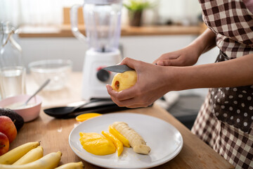 Close up of woman making fresh fruit smoothies in blender in kitchen. 