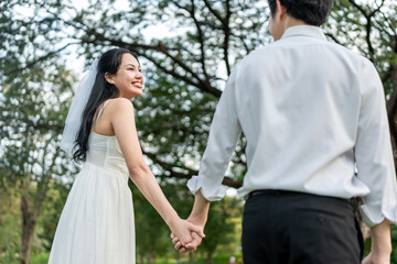 Asian young married couple holding hand each other in park during sunset. 
