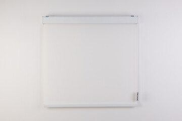 Blinds on a white wall in a room.