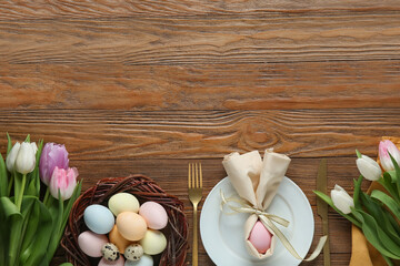 Stylish table setting for Easter celebration with tulip flowers on wooden background