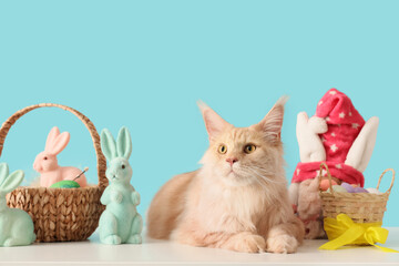 Cute Maine Coon cat with Easter baskets and toys on table against blue background