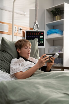 Young patient playing videogames in hospital bed