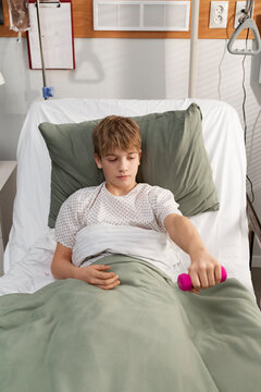Young patient lifting weights during recovery in hospital bed