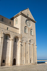 Fototapeta premium Trani Cathedral, a stunning Romanesque masterpiece in Apulia, Italy, stands majestically by the Adriatic Sea, showcasing its elegant limestone façade and historic charm.