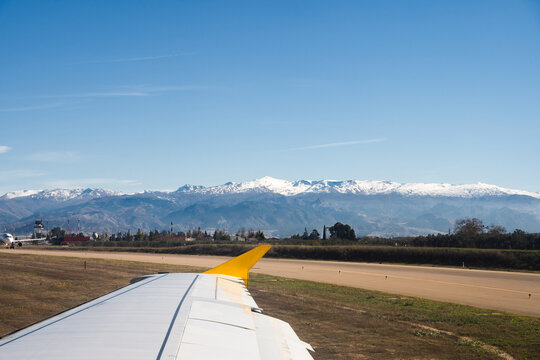 Airplane taxiing on runway with snowy mountains in background