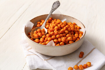 Bowl with tasty fried chickpeas on white wooden background