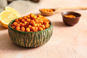 Bowl with tasty fried chickpeas and lemon on beige background