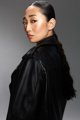 Fototapeta premium Fashion asian woman black leather jacket posing for camera side glance portrait of stylish asian woman in black leather jacket, looking off to the side