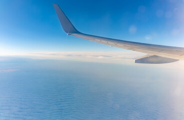 Obraz premium View from the airplane window at a beautiful cloudy sky and the airplane wing