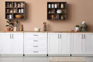 Interior of kitchen with white counters, shelves and utensils