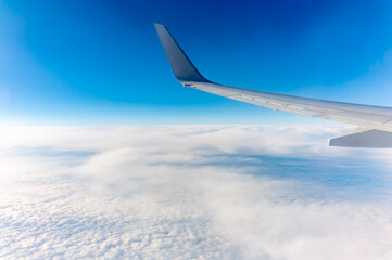 View from the airplane window at a beautiful cloudy sky and the airplane wing