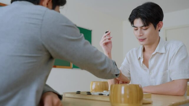 Asian young men playing board game Go during competition in community. 