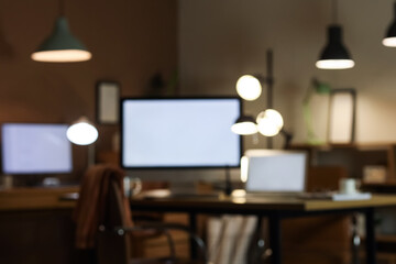 Blurred view of office with workplace and glowing lamps