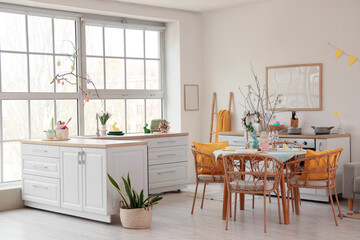 Interior of light kitchen decorated for Easter with dining table and counters