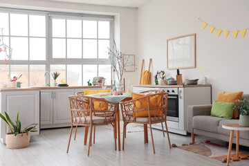 Interior of light kitchen decorated for Easter with dining table, sofa and counters