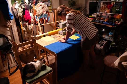 Woman Marking Blue Fabric with a Cat Nearby
