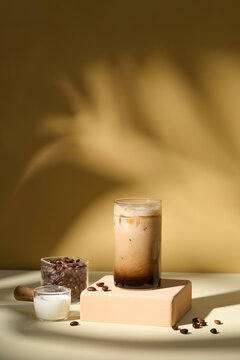 Iced Coffee with Milk and Coffee Beans on Yellow Background