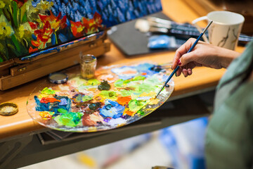 Artist Mixing Colors on Palette for Floral Painting Creation