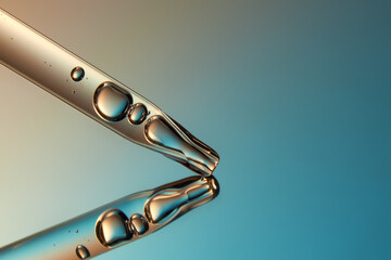 Close up of a pipette with liquid on reflective blue background.