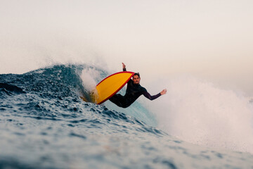 Expert surfer doing a reentry on the crest of a huge wave