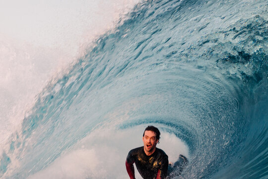 Bodyboarder skillfully riding a massive wave, tucked inside a tube