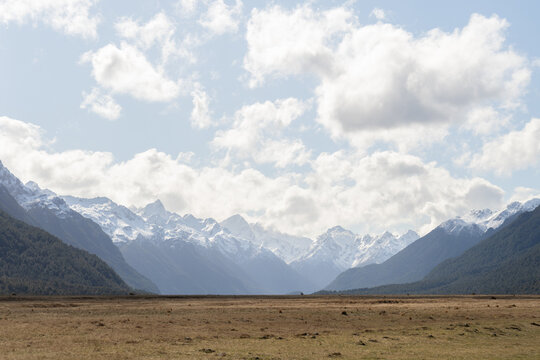 Dry grassland surrounded by snowy mountain peaks