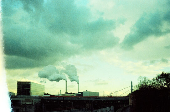 Industrial buildings with smokestacks against cloudy sky