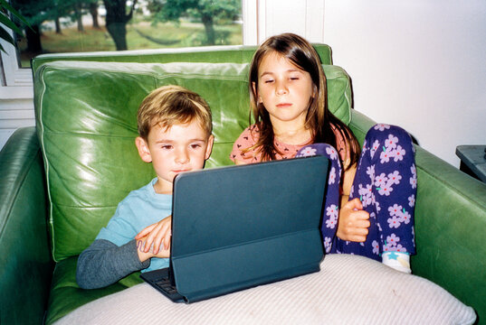 Direct flash film photo of two kids watching streaming media on tablet