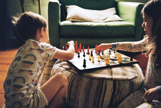 Young brother and sister playing a pretend game of chess together