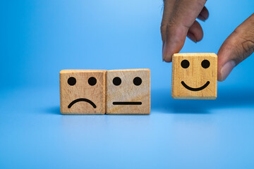 sad, flat and happy face expression emoticon on wooden cubes isolated on black dark background