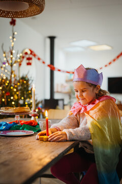young girl smiling in party outfit with a lit candle.