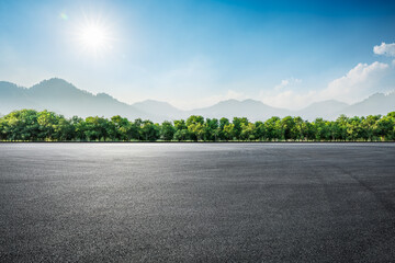 Asphalt road and green trees with mountain background © ABCDstock