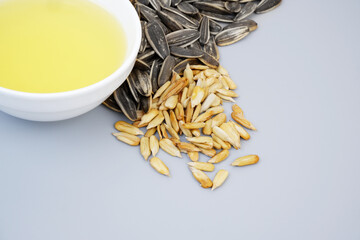 Sunflower seeds and oil in bowl on gray background, copy space for text.