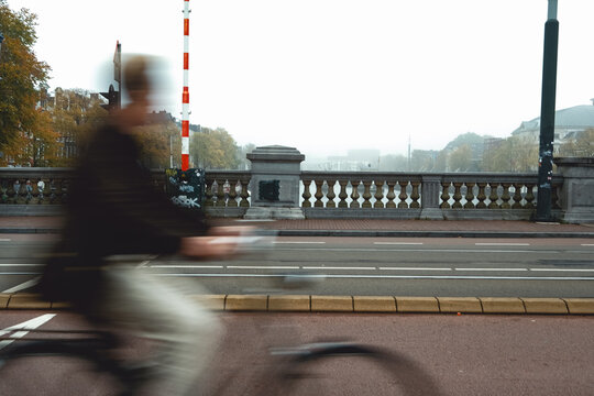 Blurred Cyclist on Foggy City Bridge