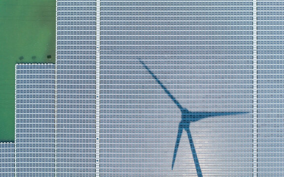 Floating Solar Farm With Wind Turbine Shadow Aerial Drone View