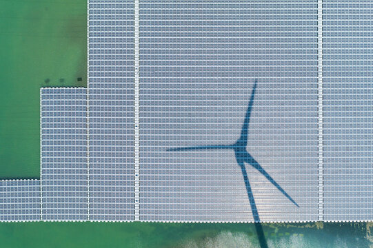 Floating Solar Farm With Wind Turbine Shadow Aerial Drone View