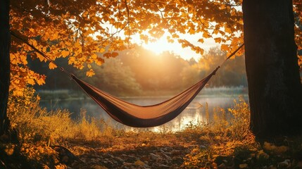 Hammock hanging between trees by lake at sunset during fall