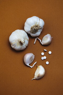 Garlic Bulbs and Tablets on Brown Background