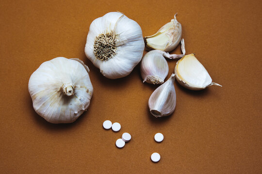 Garlic Bulbs and White Tablets on Brown Surface
