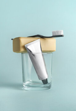 Toothbrush, soap and cream tube in a glass against a blue background