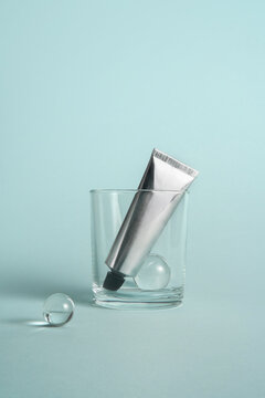 Silver tube in a glass on a pastel blue background. 