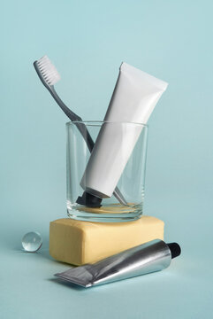 Toothbrush, soap and cream tubes in a glass against a blue background