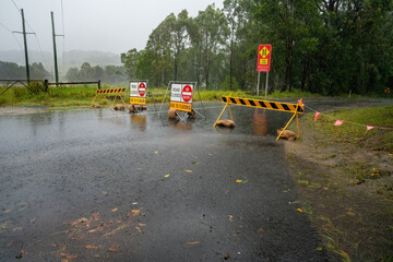 A road is barricaded off with a warning of the road being flooded ahead