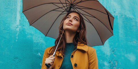 A woman is holding an umbrella and looking up at the sky