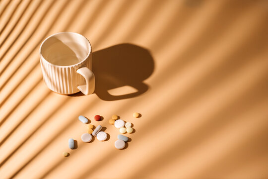 A lot of medicine and cup of water at beige background. 