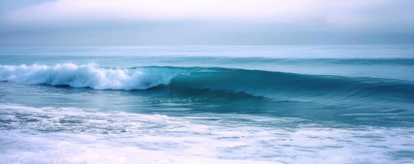 Fototapeta premium Seascape abstract background concept. A serene ocean wave gently rolls onto a tranquil sandy shore at sunrise.