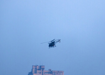 helicopter flying on isolated blue sky over a building